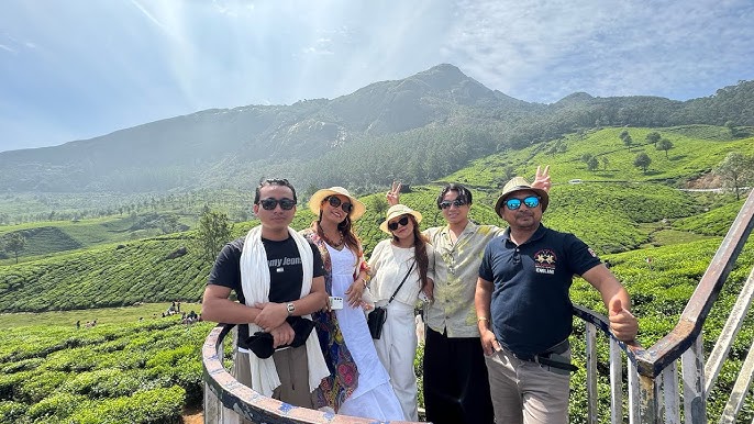 Friends posing at a scenic tea plantation during a Munnar photoshoot with mountain views