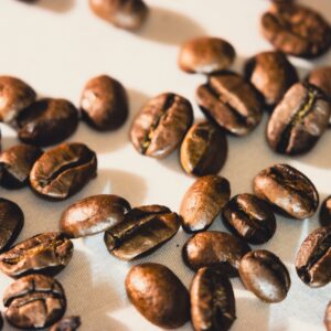 Bright close-up of roasted coffee beans scattered on white surface, ideal for coffee-themed designs.